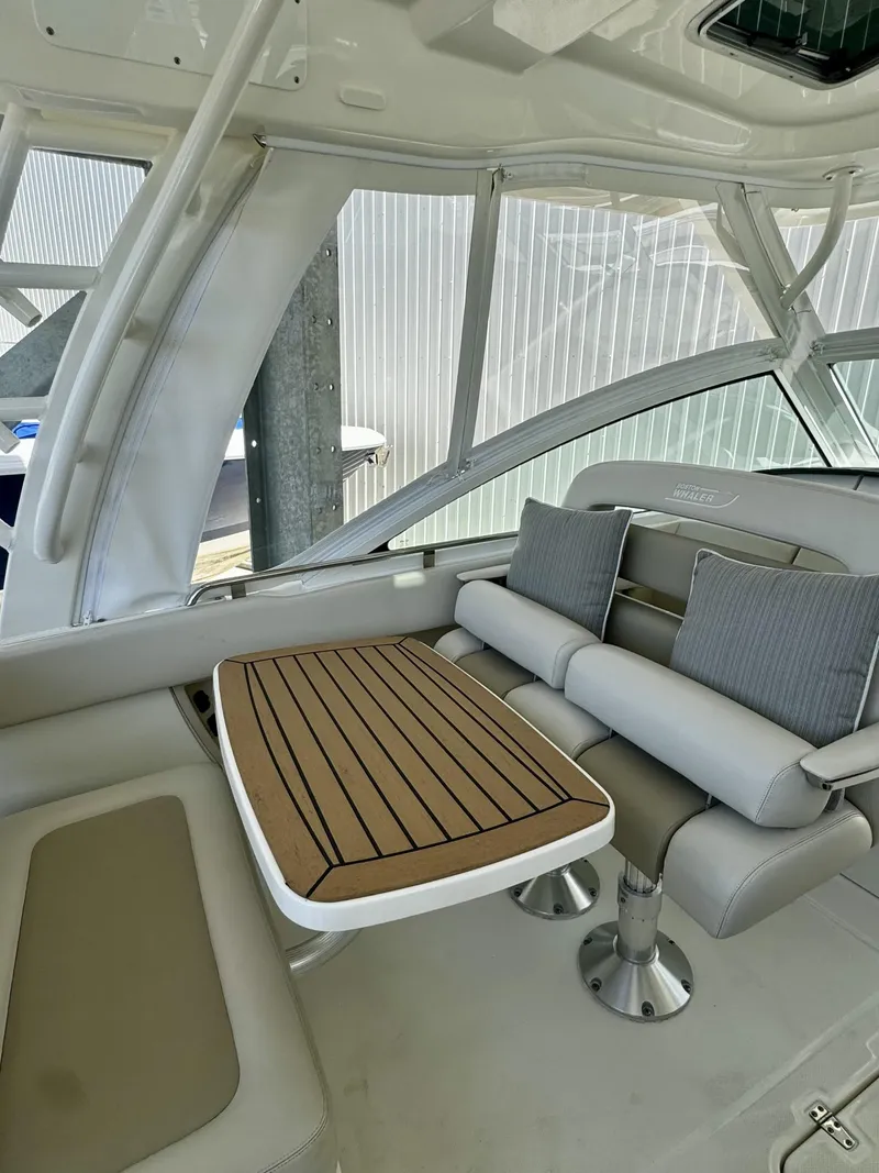 Slide: The Image of 2016 Boston Whaler 320 Vantage interior with cushioned seating and wooden table. - 28