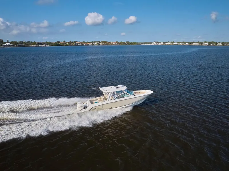 Slide: The Image of 2016 Boston Whaler 320 Vantage cruising on a calm lake under a clear blue sky. - 41