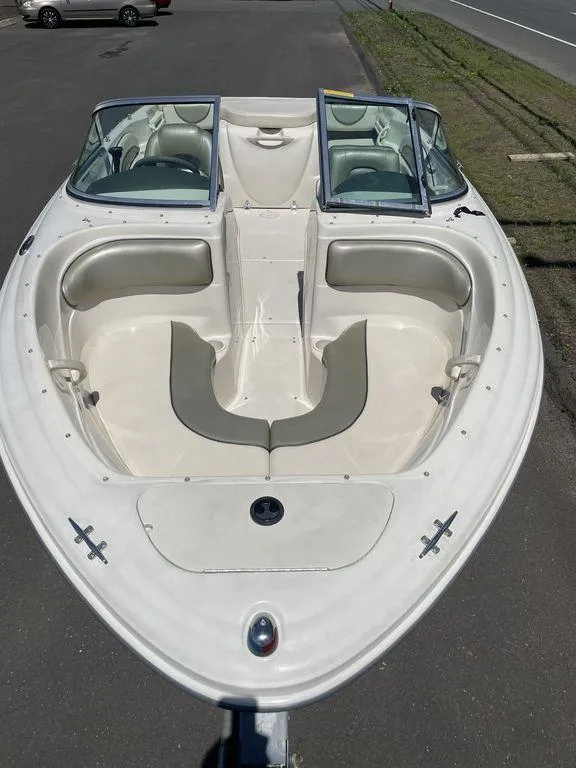 Slide: The Image of 2004 Sea Ray 185 Sport boat, white exterior, spacious seating, parked on pavement. - 12