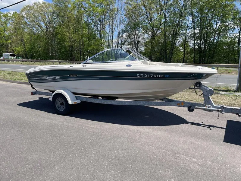 Slide: The Image of 2004 Sea Ray 185 Sport boat on trailer, parked on road with trees in background. - 15