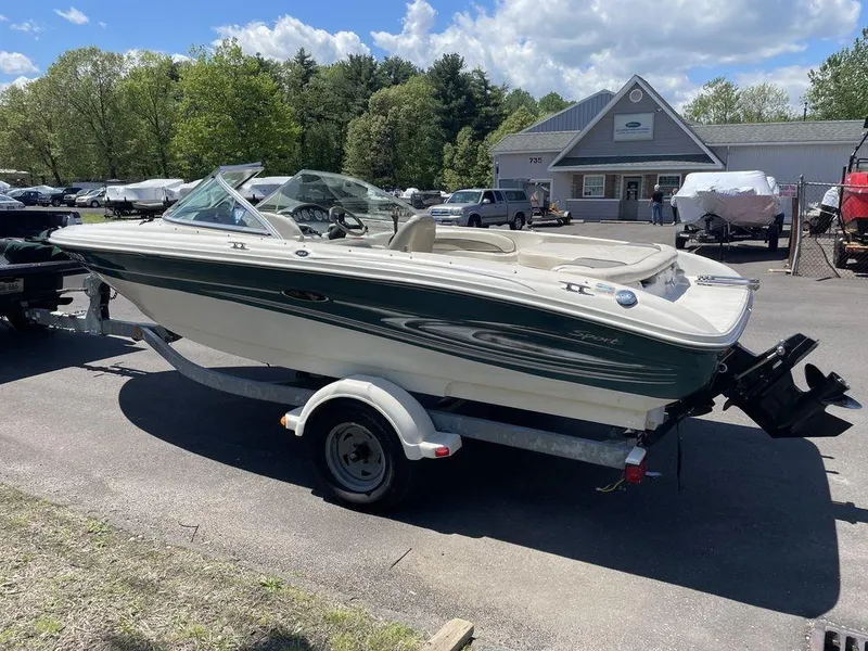 Slide: The Image of 2004 Sea Ray 185 Sport boat on trailer, parked outdoors under a partly cloudy sky. - 16