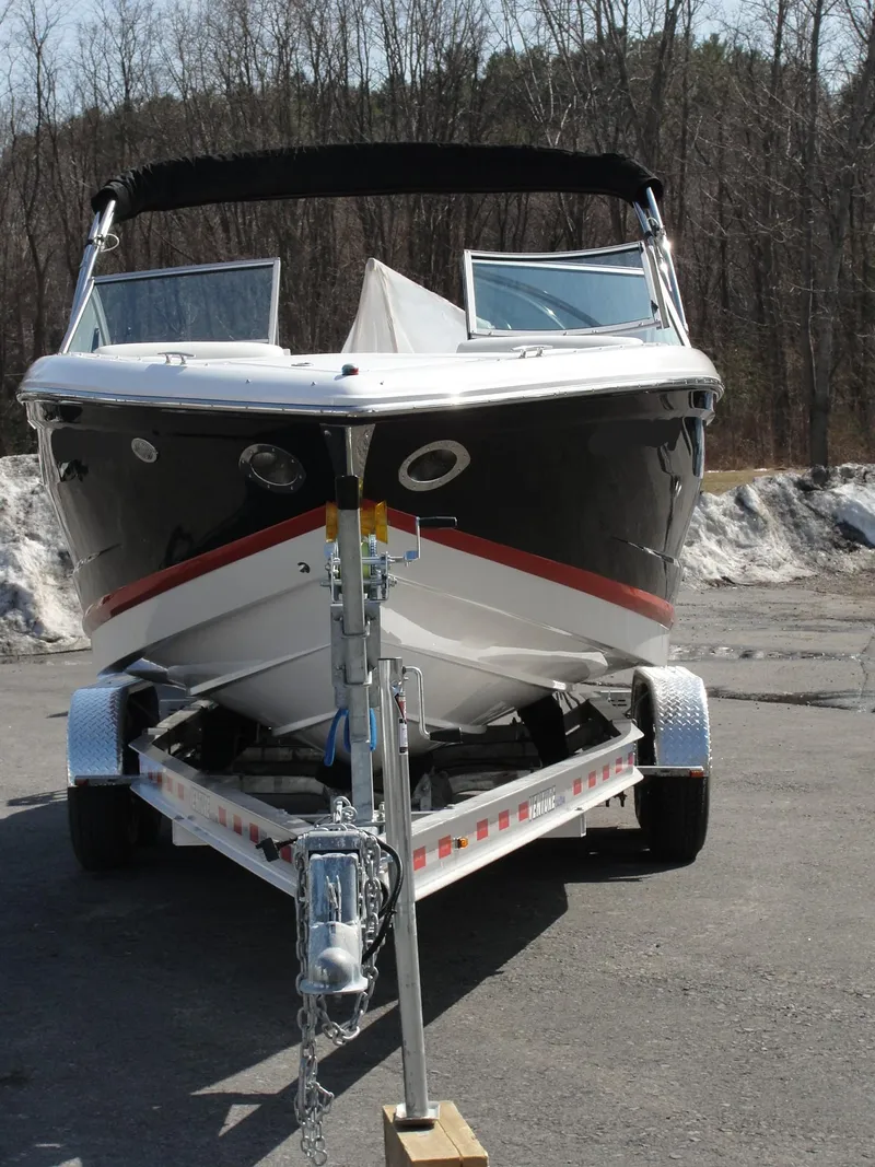 Slide: The Image of 2013 Cobalt A25 boat on trailer, parked outdoors in a wooded area. - 2
