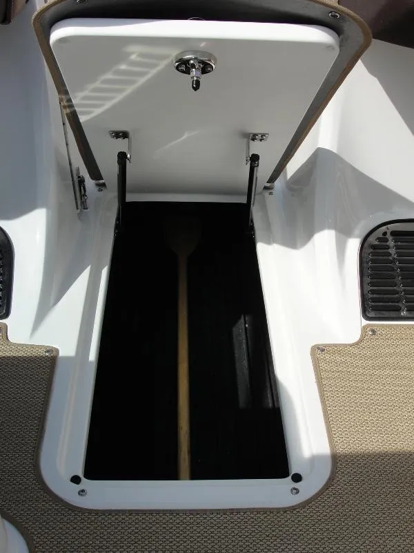 Slide: The Image of Open storage compartment on 2013 Cobalt A25 boat, showing interior space and paddle. - 36