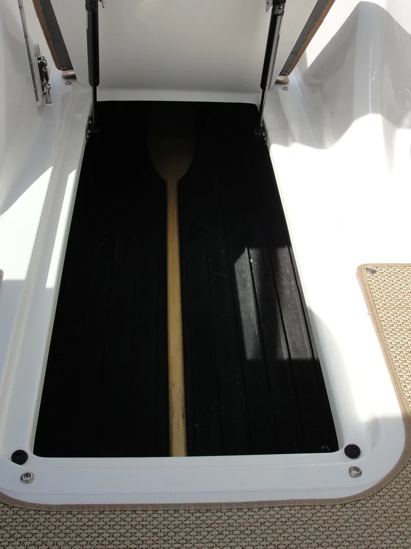 Slide: The Image of 2013 Cobalt A25 boat storage compartment with a wooden paddle inside. - 37