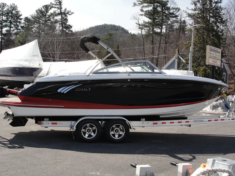 Slide: The Image of 2013 Cobalt A25 boat on trailer, black and red design, parked outdoors. - 4