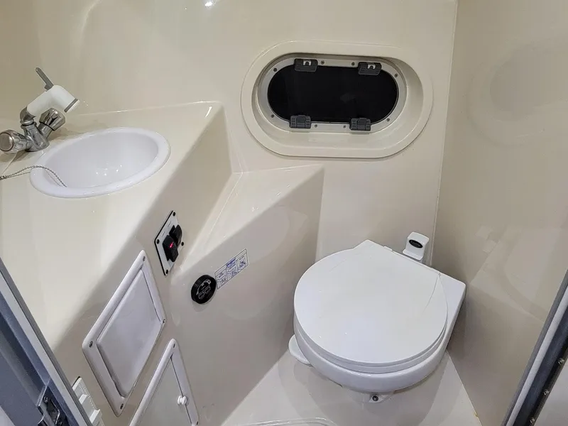Slide: The Image of 2003 Four Winns 248 Vista boat bathroom with sink, toilet, and porthole window. - 10