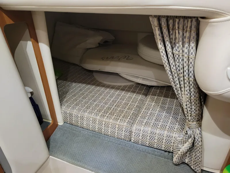 Slide: The Image of 2003 Four Winns 248 Vista cabin interior with patterned bedding and privacy curtain. - 11