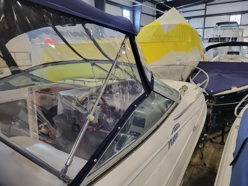 Slide: The Image of 2003 Four Winns 248 Vista boat in storage, featuring a covered cockpit and sleek design. - 16