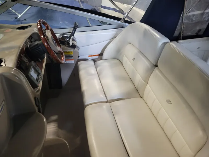 Slide: The Image of 2003 Four Winns 248 Vista boat interior with beige seating and wooden steering wheel. - 3