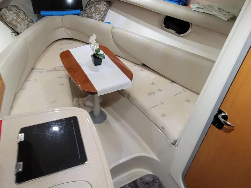 Slide: The Image of 2003 Four Winns 248 Vista cabin interior with beige seating and wooden table. - 8