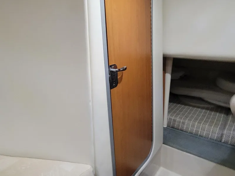 Slide: The Image of Interior cabin of 2003 Four Winns 248 Vista boat, featuring a wooden door and cozy sleeping area. - 9