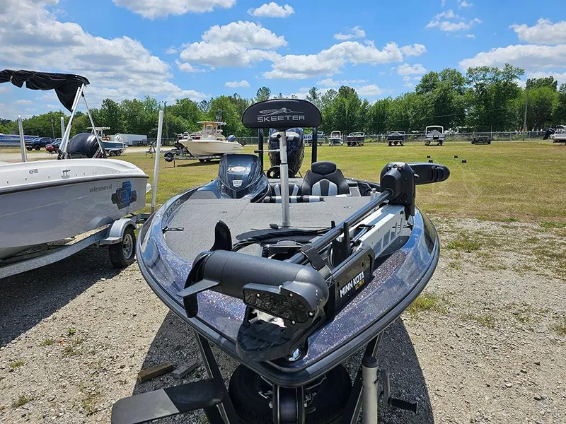 Slide: The Image of 2022 Skeeter ZX200 boat with Minn Kota trolling motor, parked outdoors under a blue sky. - 4