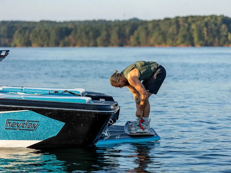 Slide: The Image of Man preparing to wakeboard on 2025 HEYDAY WAKE BOATS WT-SURF in a serene lake. - 10