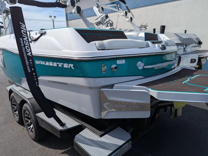 Slide: The Image of 2022 Malibu Wakesetter 23 LSV boat on trailer, teal and white design, rear view. - 3