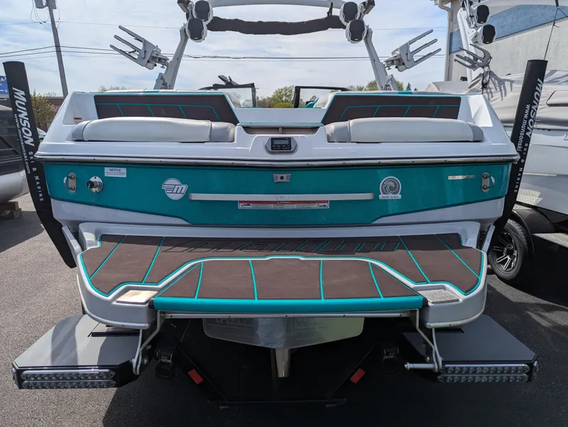 Slide: The Image of 2022 Malibu Wakesetter 23 LSV boat, rear view, teal and white design, parked outdoors. - 4