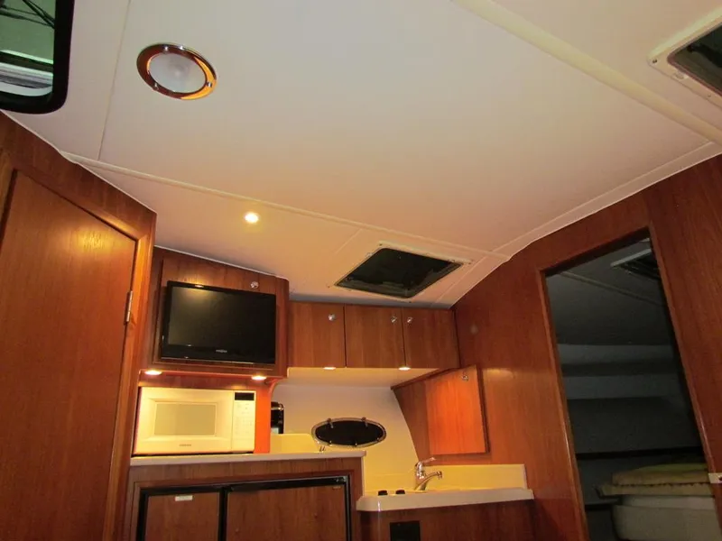 Slide: The Image of Interior of 1999 Tiara Yachts 3500 Open with wood cabinetry, TV, and kitchenette. - 30