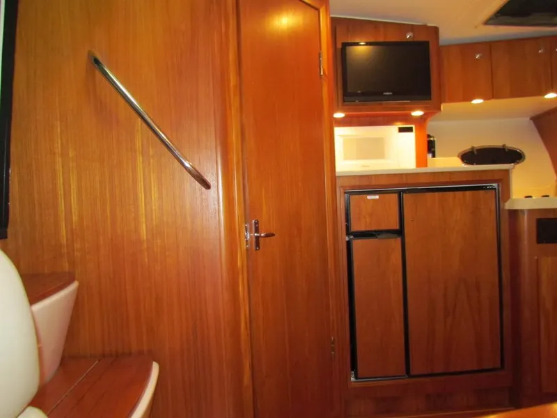 Slide: The Image of Interior of 1999 Tiara Yachts 3500 Open, featuring wood cabinetry, fridge, and microwave. - 35