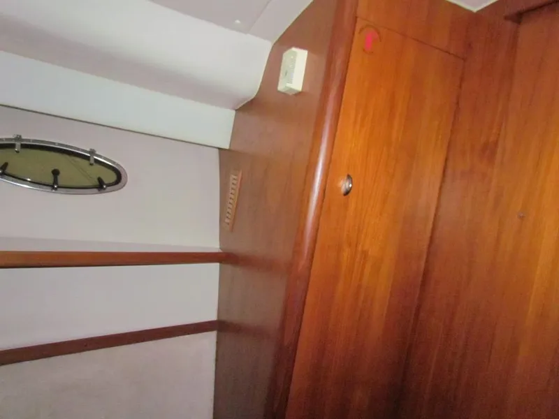 Slide: The Image of Interior of 1999 Tiara Yachts 3500 Open, featuring wooden paneling and a porthole window. - 42