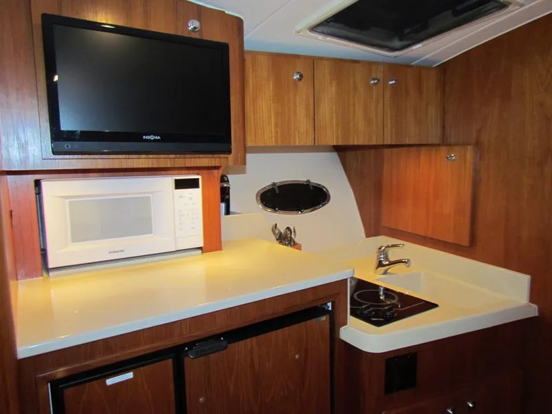 Slide: The Image of 1999 Tiara Yachts 3500 Open galley with TV, microwave, and compact kitchen amenities. - 43
