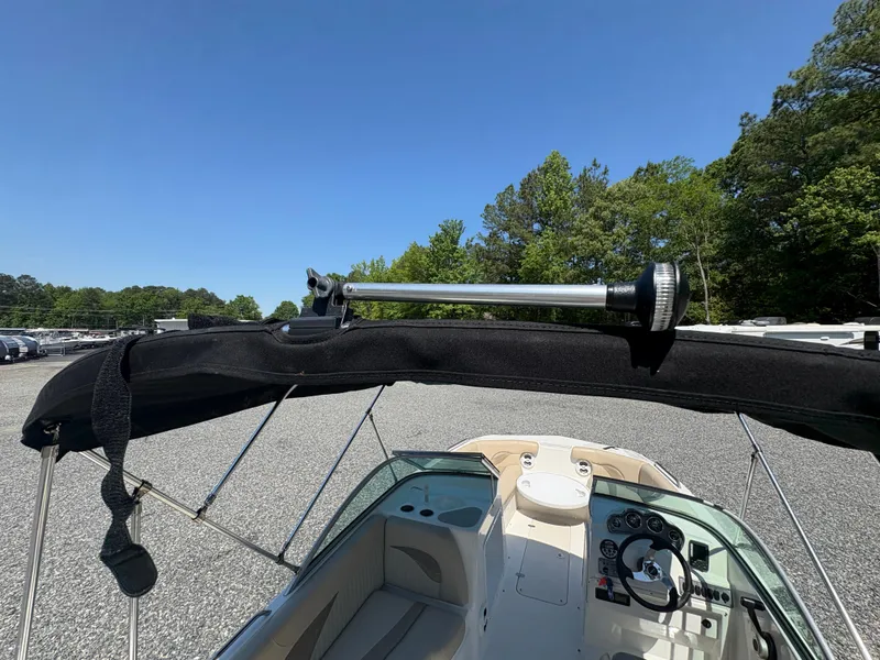 Slide: The Image of 2017 NauticStar 203 DC boat with bimini top, parked outdoors under clear blue sky. - 11
