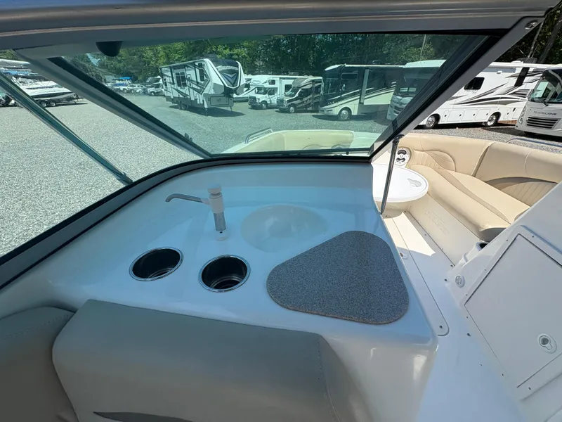 Slide: The Image of 2017 NauticStar 203 DC boat interior with sink and cup holders, parked near RVs. - 13