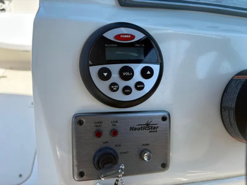Slide: The Image of Control panel of a 2017 NauticStar 203 DC boat with audio and ignition controls. - 17