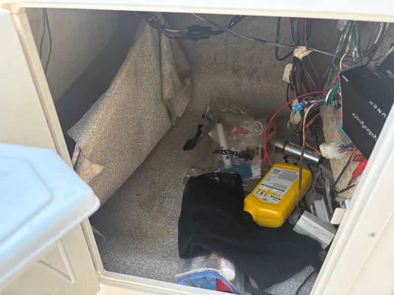 Slide: The Image of Storage compartment of a 2017 NauticStar 203 DC boat with various items and wiring. - 20