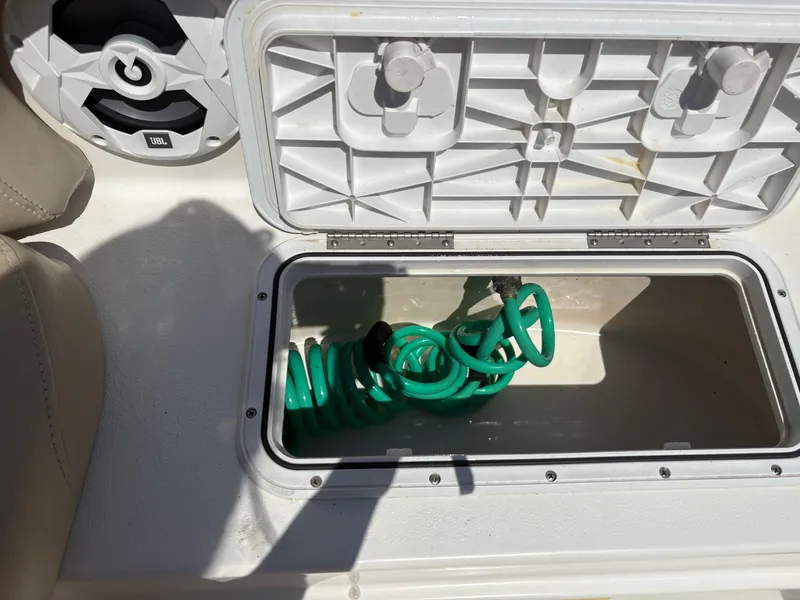 Slide: The Image of Storage compartment with green hose in 2017 NauticStar 203 DC boat. - 22