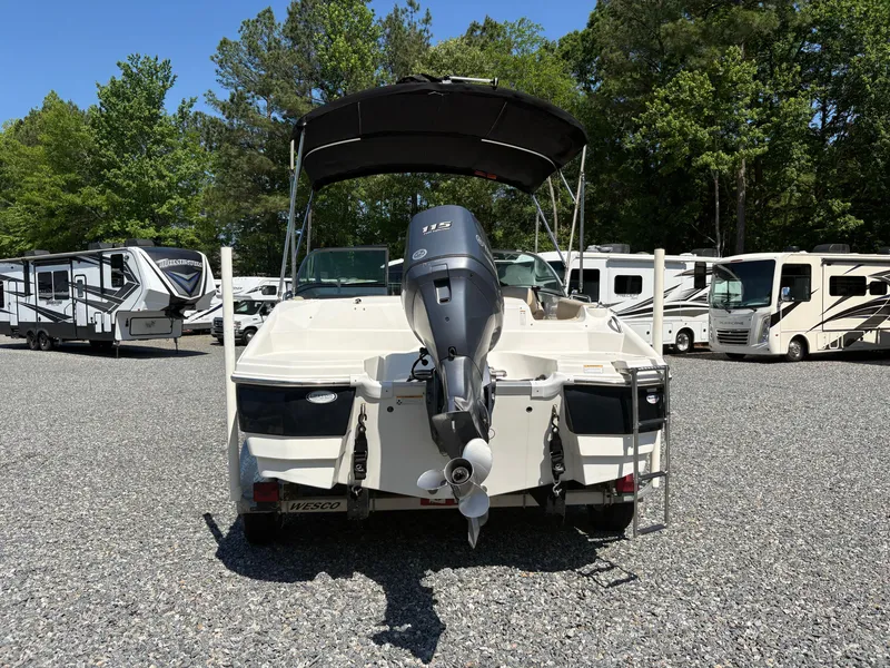 Slide: The Image of 2017 NauticStar 203 DC boat with outboard motor, parked among RVs and trees. - 3