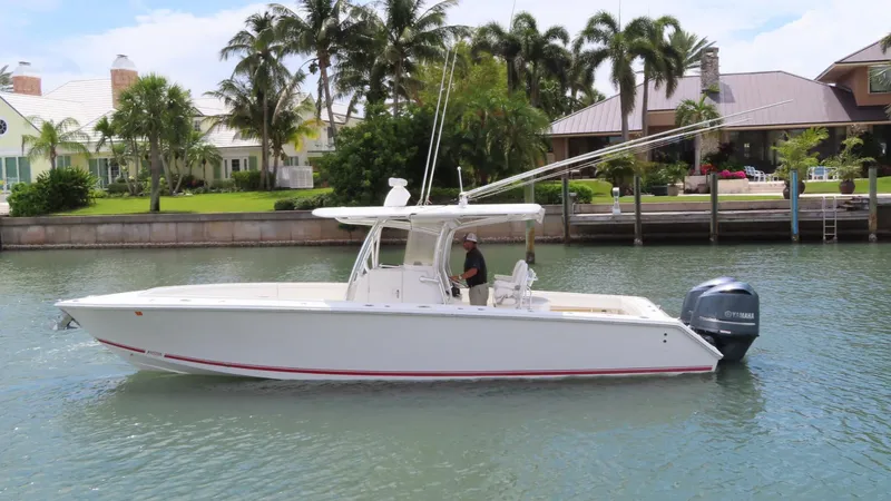 Slide: The Image of 2013 Jupiter 34 boat cruising on a canal with palm trees and houses in the background. - 1