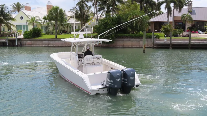 Slide: The Image of 2013 Jupiter 34 boat with dual outboard motors cruising in a scenic waterfront area. - 24