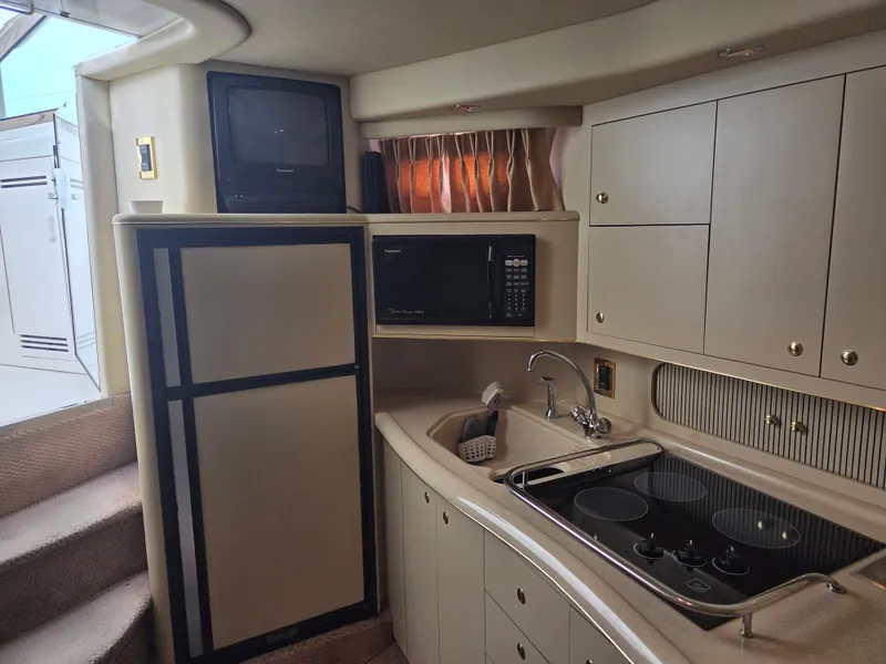 Slide: The Image of 1998 Sea Ray 400 Sundancer kitchen with stove, microwave, and fridge. - 27