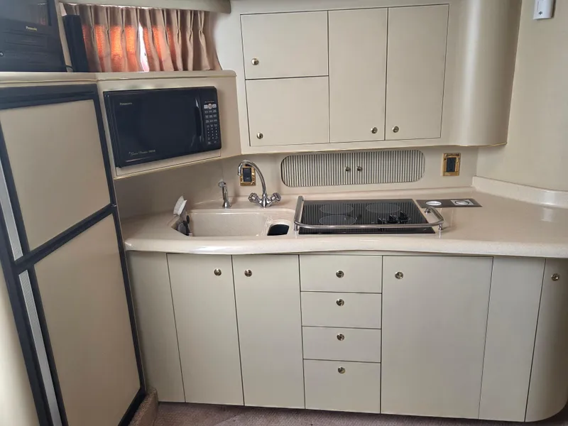 Slide: The Image of 1998 Sea Ray 400 Sundancer kitchen with microwave, sink, and stove. - 28