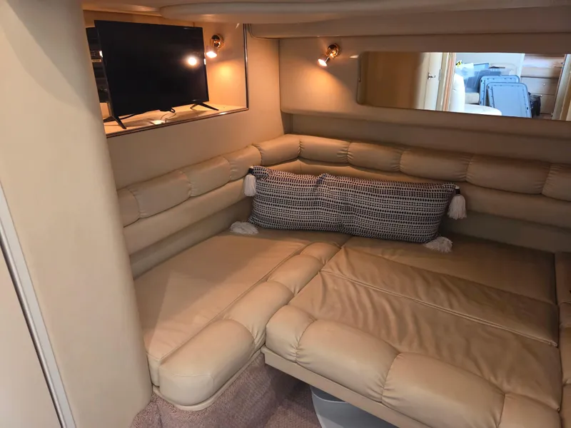 Slide: The Image of 1998 Sea Ray 400 Sundancer interior with beige seating, TV, and decorative pillows. - 30