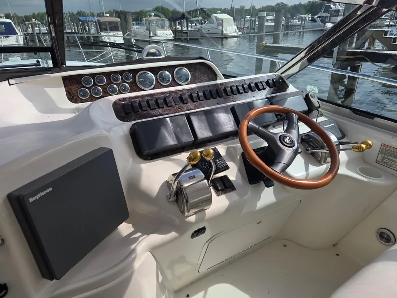 Slide: The Image of 1998 Sea Ray 400 Sundancer helm with wood steering wheel and marina view. - 9