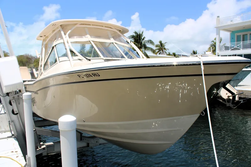 Slide: The Image of 2019 Grady-White Freedom 275 boat docked, clear sky, palm trees in background. - 0
