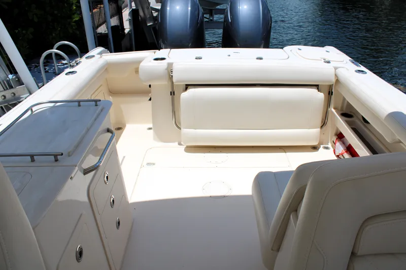 Slide: The Image of 2019 Grady-White Freedom 275 boat interior with seating and storage, docked by the water. - 12