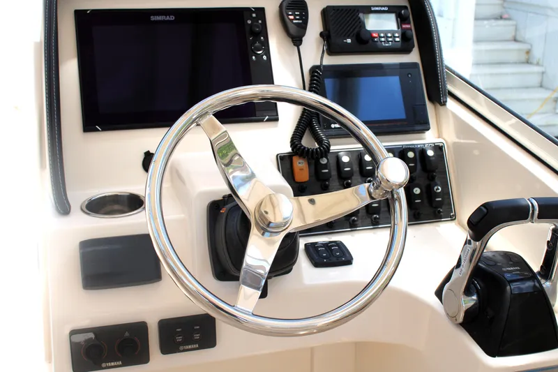 Slide: The Image of 2019 Grady-White Freedom 275 boat dashboard with steering wheel and electronic controls. - 31