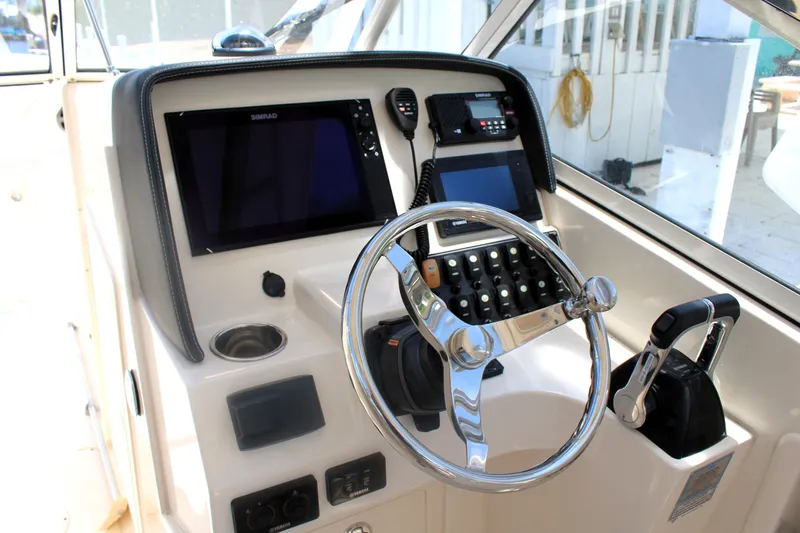 Slide: The Image of 2019 Grady-White Freedom 275 boat dashboard with steering wheel and navigation controls. - 34