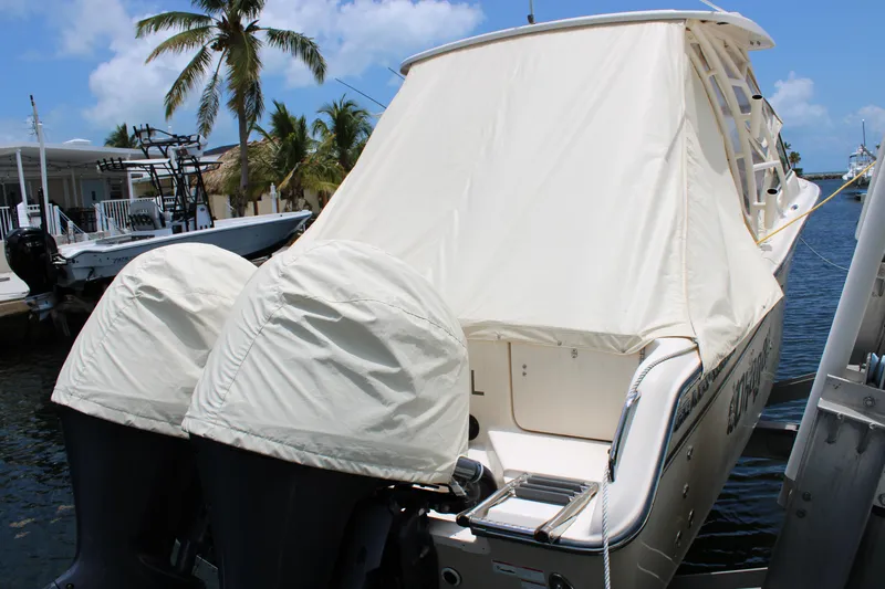 Slide: The Image of 2019 Grady-White Freedom 275 boat with covered engines docked by palm trees. - 4