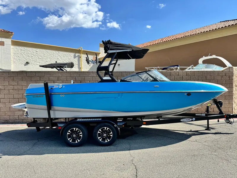 Slide: The Image of 2021 Moomba Craz boat in vibrant blue on a trailer, parked outdoors. - 0