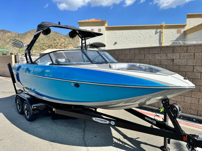 Slide: The Image of 2021 Moomba Craz boat in blue on trailer, parked outdoors under clear sky. - 1