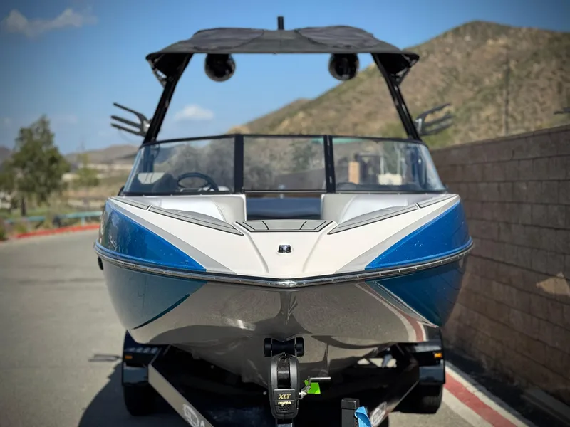 Slide: The Image of 2021 Moomba Craz boat with blue accents on a trailer, parked near a mountain road. - 2