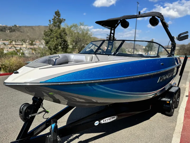 Slide: The Image of 2021 Moomba Craz boat with blue exterior on a trailer, parked outdoors. - 3