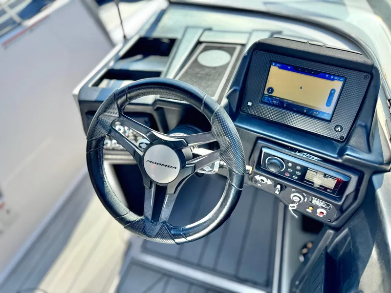 Slide: The Image of 2021 Moomba Craz boat dashboard with steering wheel and navigation display. - 30