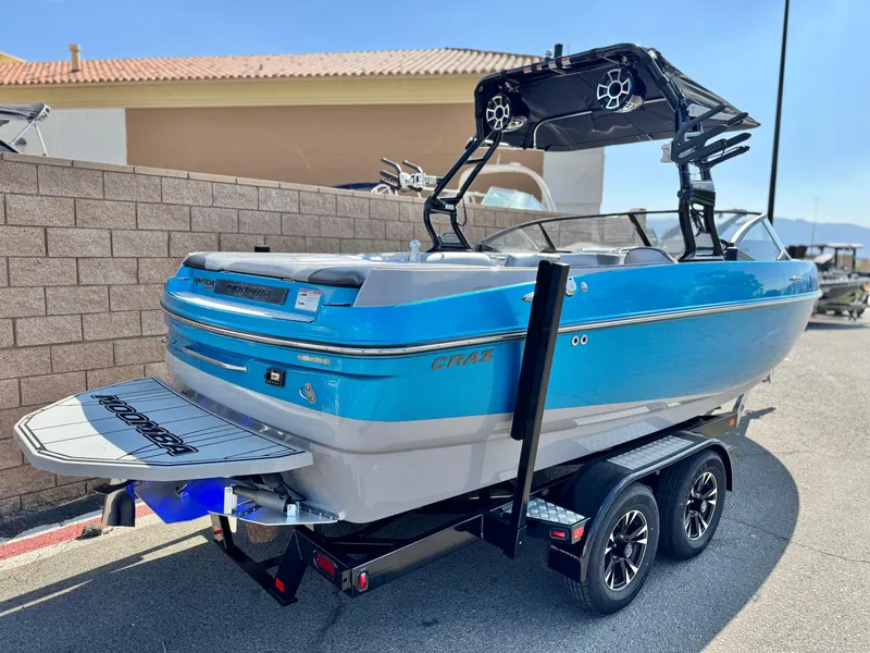 Slide: The Image of 2021 Moomba Craz boat on trailer, blue and white, parked outdoors. - 5