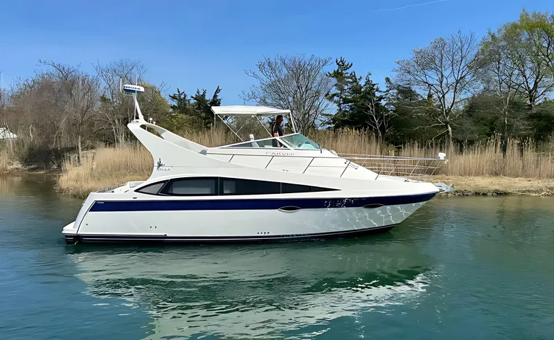 Slide: The Image of 2008 Carver 36 Mariner yacht cruising on a serene waterway with trees in the background. - 1