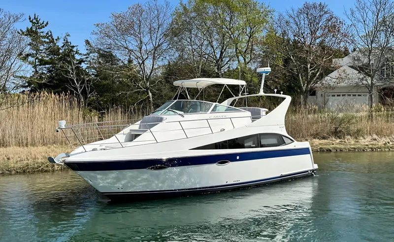 Slide: The Image of 2008 Carver 36 Mariner yacht on a serene waterway, surrounded by trees and reeds. - 2