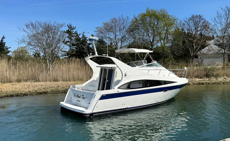 Slide: The Image of 2008 Carver 36 Mariner yacht on a serene waterway, surrounded by trees. - 7