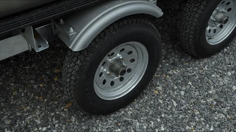 Slide: The Image of Trailer wheels of a 2025 Tahoe Pontoon Aura 2185 Quad Lounger Triple on gravel. - 25